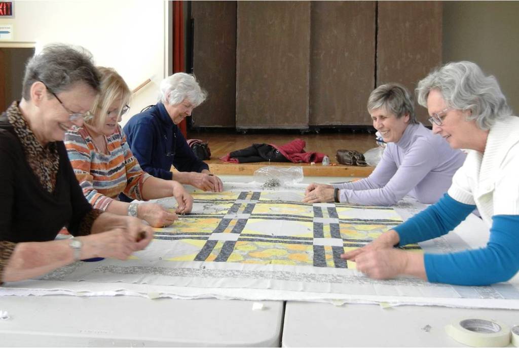 Volunteers pinning together a quilt