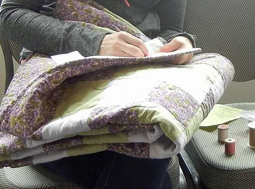 Volunteer sewing binding onto quilt